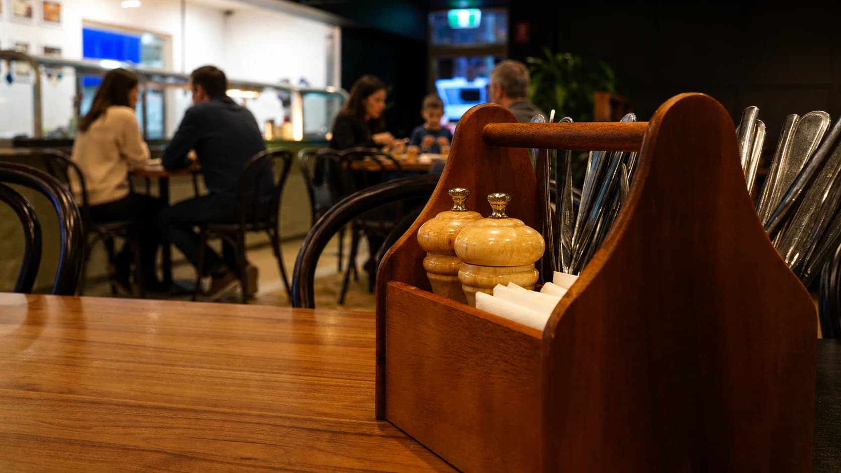 A timber dining table set with cutlery inside the bistro